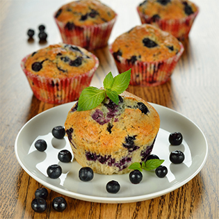 Blueberry Muffins auf Teller und in Papierförmchen mit Blaubeeren