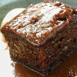 Sticky Toffee Pudding Stück mit Puderzucker auf Teller