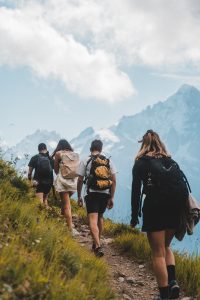 Gruppe von Wanderern auf grünem Bergpfad mit Rucksäcken