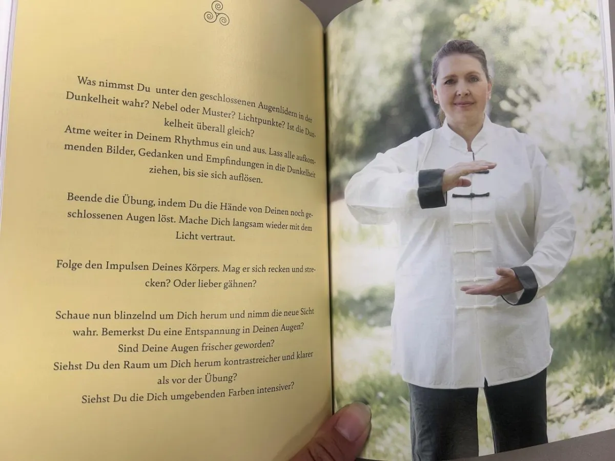 Aufgeschlagenes Buch mit beiger Seite und Frau in weißer Bluse, die Hände neutral hält, grüner Hintergrund
