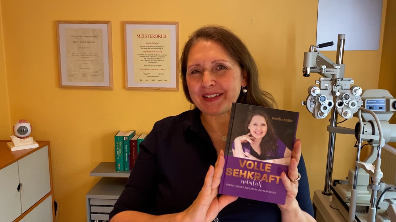 Kerstin Müller hält das Buch Volle Sehkraft natürlich in ihrer Praxis mit Meisterbrief und Messgeräten