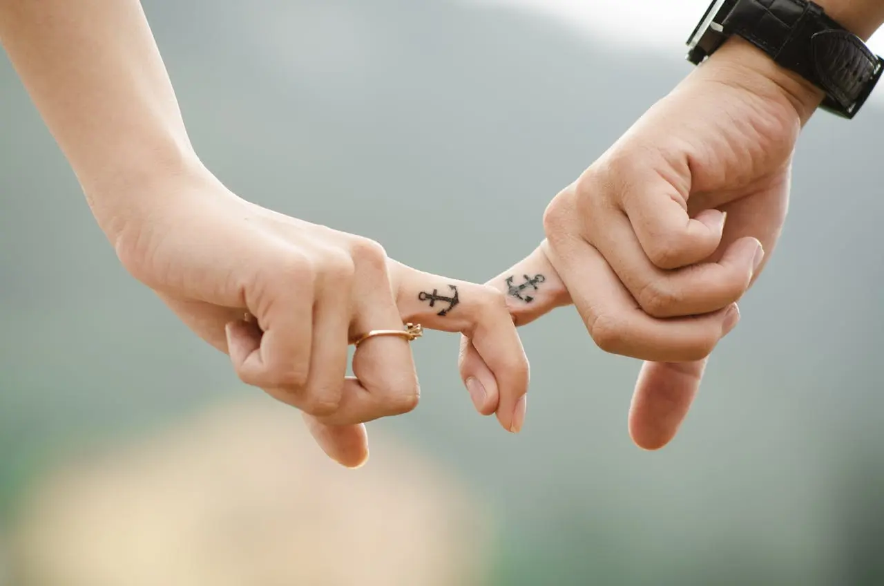 Zwei Hände halten sich mit Anker-Tattoos, Symbol für Verbindung und Partnerschaft