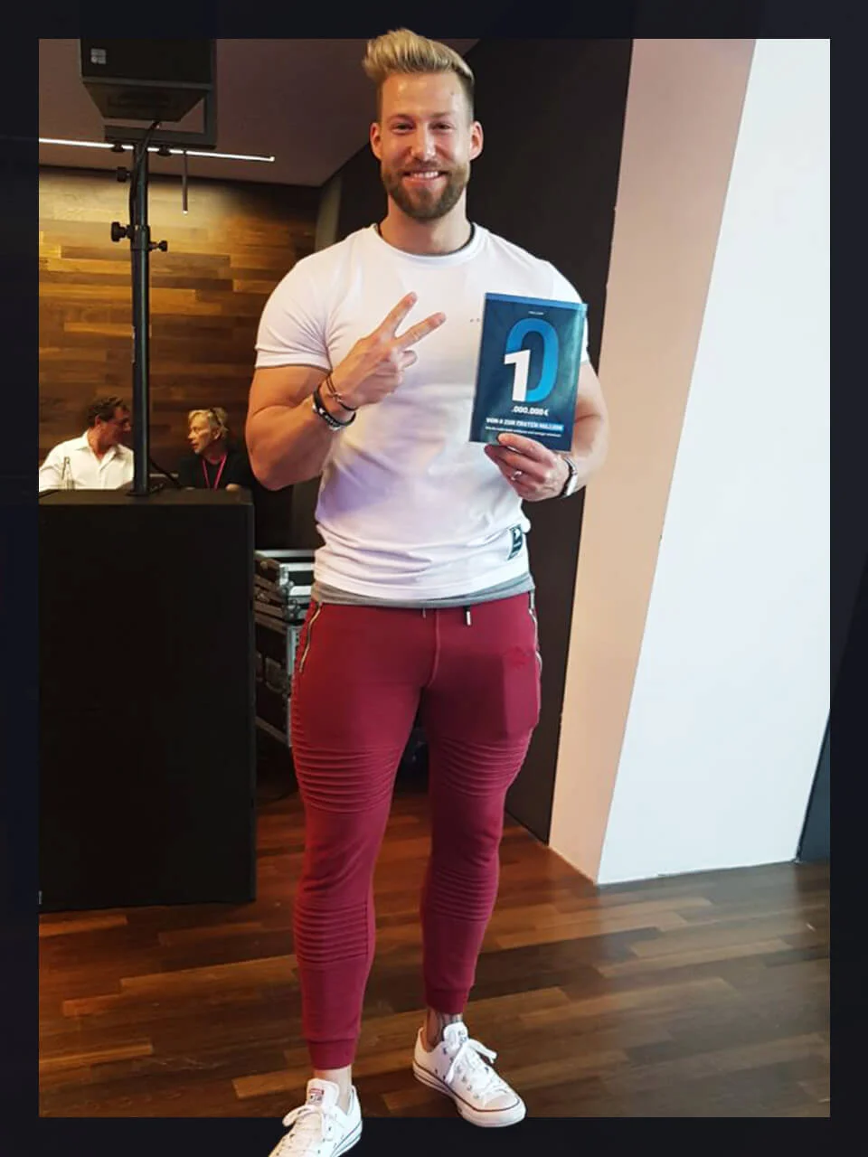 Blonder Mann im weißen T-Shirt zeigt Peace-Zeichen mit blauem D-Hörbuch-Cover