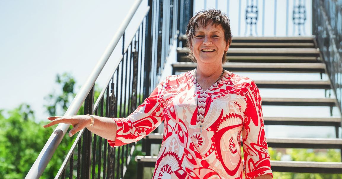 Steffi Christian in rotem Muster-Oberteil an Treppe, Coaching-Angebot