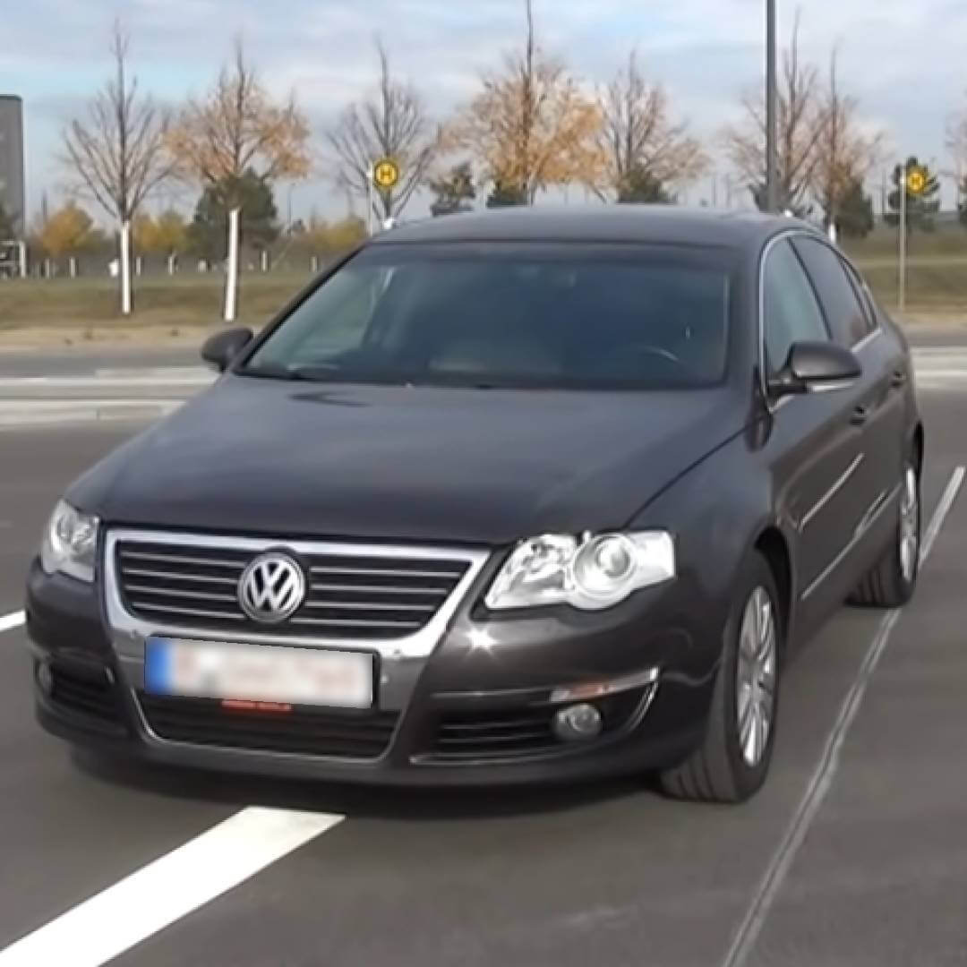 VW Passat B6 schwarzer Wagen auf Parkplatz mit kahlen Bäumen im Hintergrund