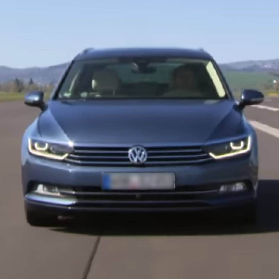 Blauer VW Passat B8 von vorne auf der Straße mit Landschaftshintergrund