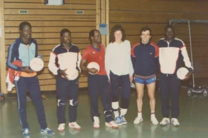 Volleyball-Team, sechs Personen mit Bällen, Sporthalle mit Holzwand, Gruppenfoto aus den 1970ern