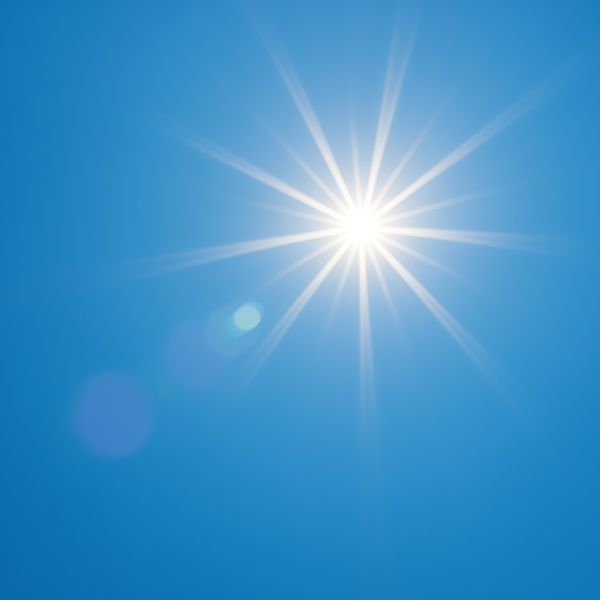 Strahlende Sonne am blauen Himmel mit Lichteffekten