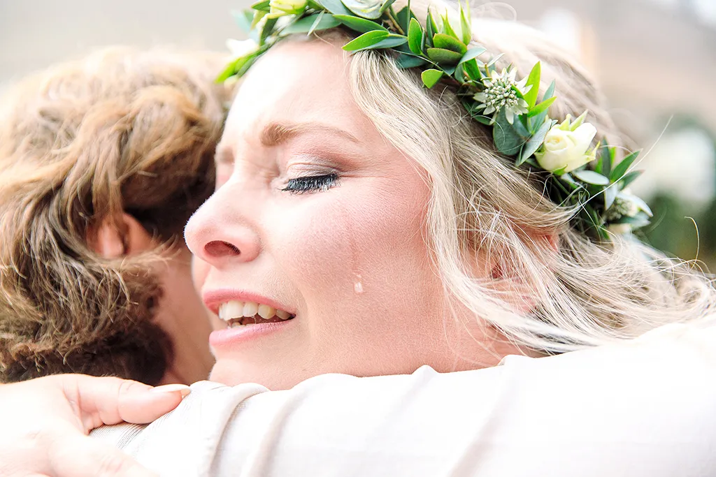Braut mit Blumenkranz und lachendem Gesichtsausdruck beim Hochzeitsfotoshooting