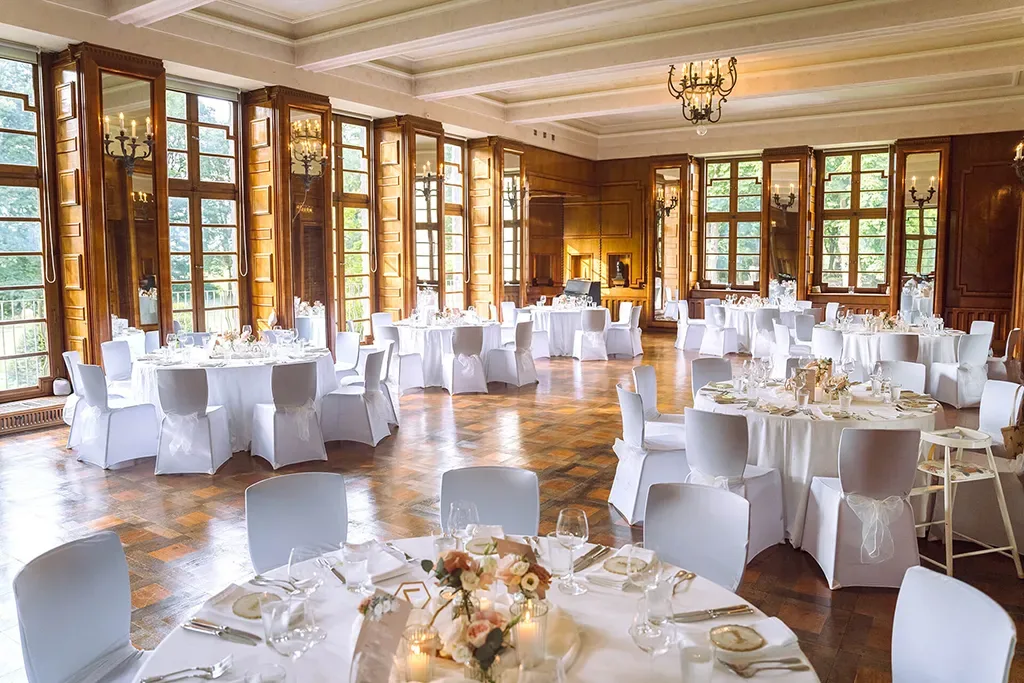 Festsaal mit weißen Tischen und eleganter Dekoration in Burg Namedy