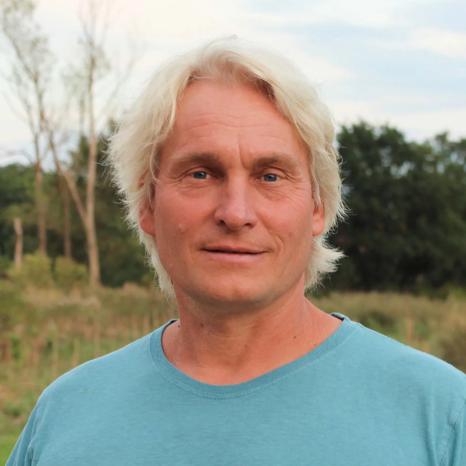 Porträt des Kursleiters Uwe Albrecht in hellblauem Shirt vor Naturhintergrund