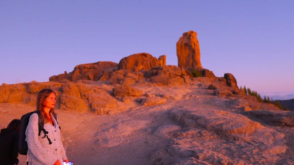 Frau vor großem Felsen bei Sonnenuntergang, spirituale Naturverbindung