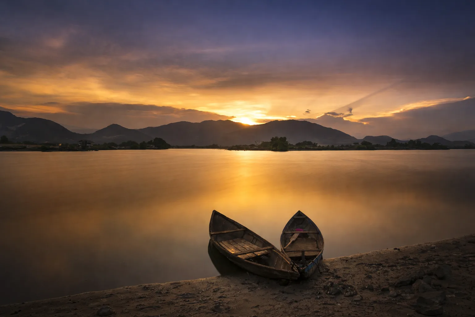 Wenn dein Hund gehen musste – Audiopaket mit E-Book 3 Sonnenuntergang über einem See mit zwei Ruderbooten am Ufer und Bergen im Hintergrund
