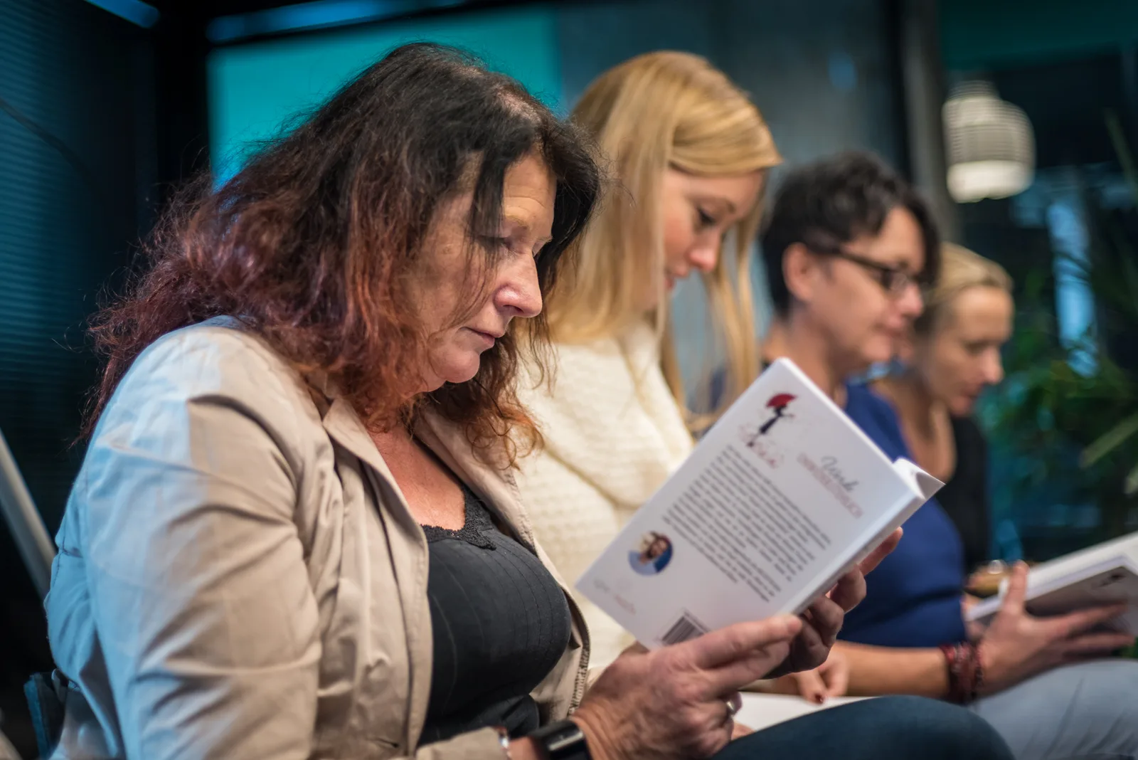 Frauen während einer Live-Veranstaltung lesen Unterlagen zum Coaching-Programm