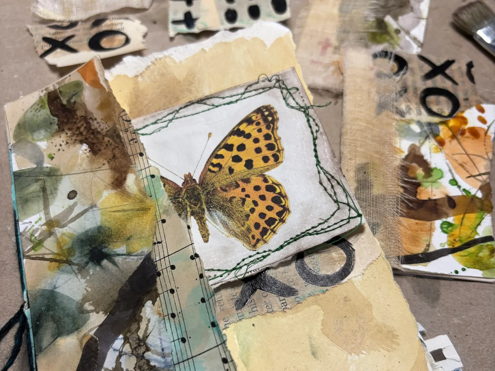 Art-Journal-Seite mit handgemaltem gelb-schwarzem Schmetterling, Musical-Noten und getrockneten Pflanzen auf strukturiertem H