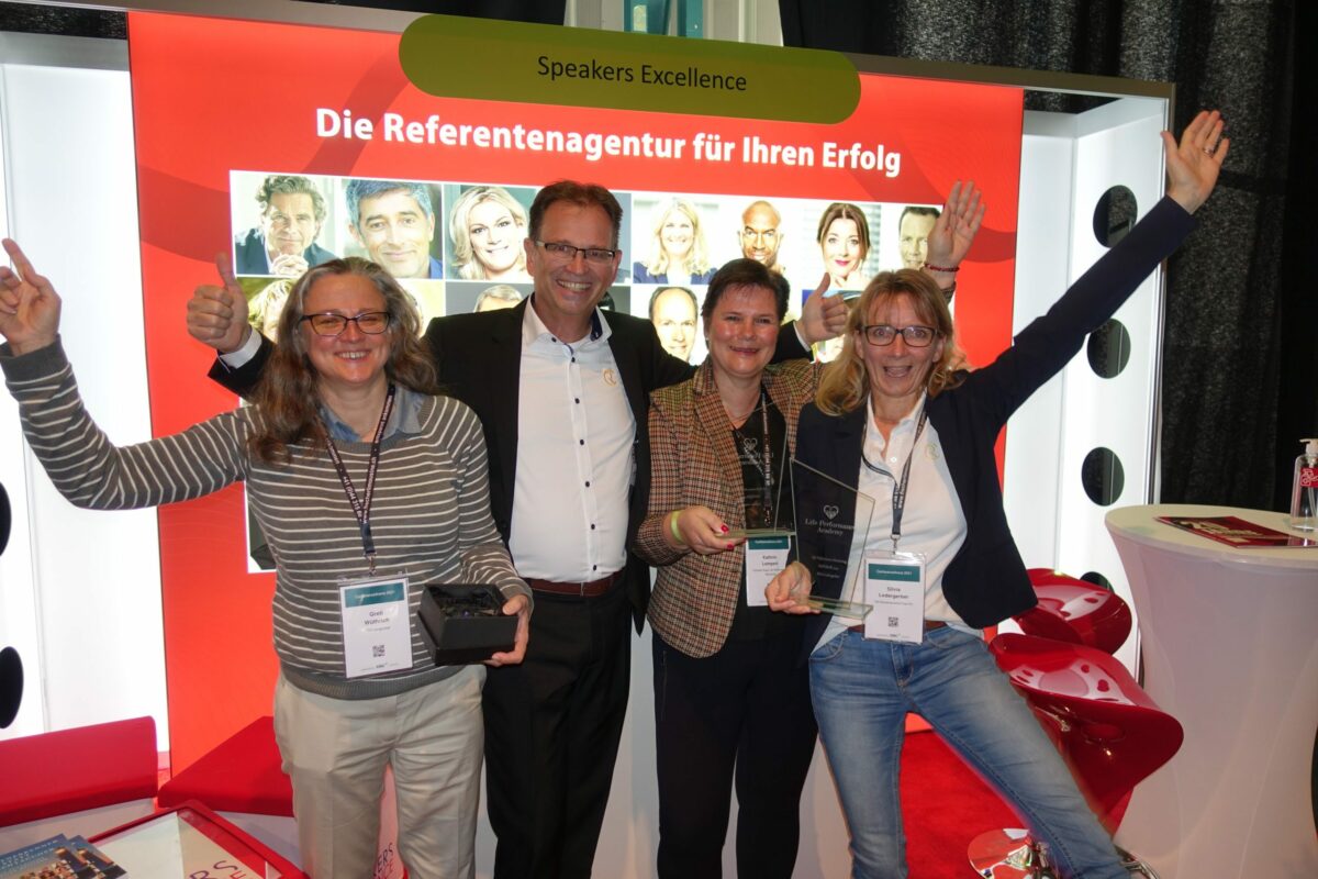 Auszeichnungsveranstaltung mit vier Kundinnen und Christian Rupp vor Speakers Excellence Banner