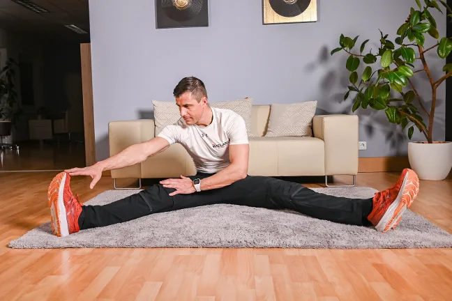 Mann in Spagat-Position dehnt Beine, Flexibilitätstraining