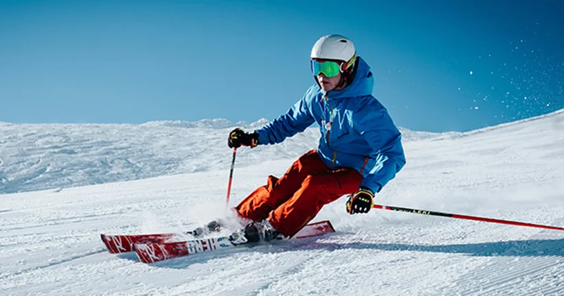 Skifahrer in blauer Jacke und roter Hose auf schneebedecktem Berg, Hochleistung