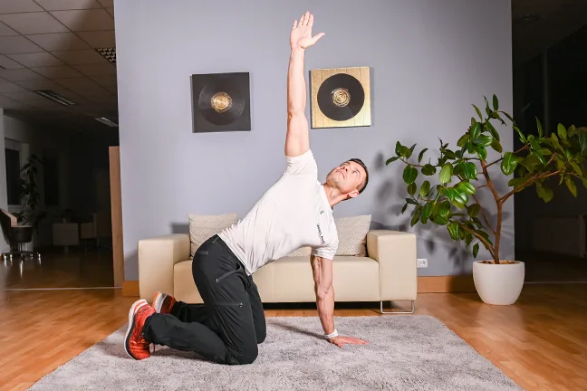Mann in Seitplank-Position auf grauer Matte mit Trainingsschleife, Funktionstraining
