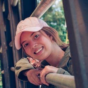 Porträtfoto einer jungen Frau mit Basecap und Lächeln im Freien