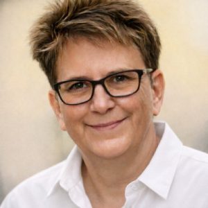 Porträt Sigrid Stiel, Frau mit kurzen Haaren und Brille vor weißem Hintergrund