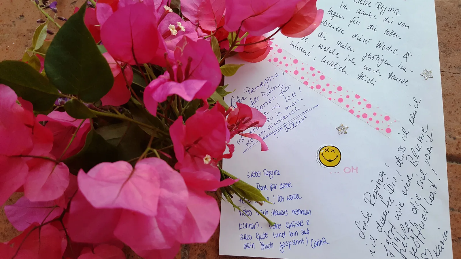 Handgeschriebene Kundenstimme auf weißem Papier mit pinken Blüten