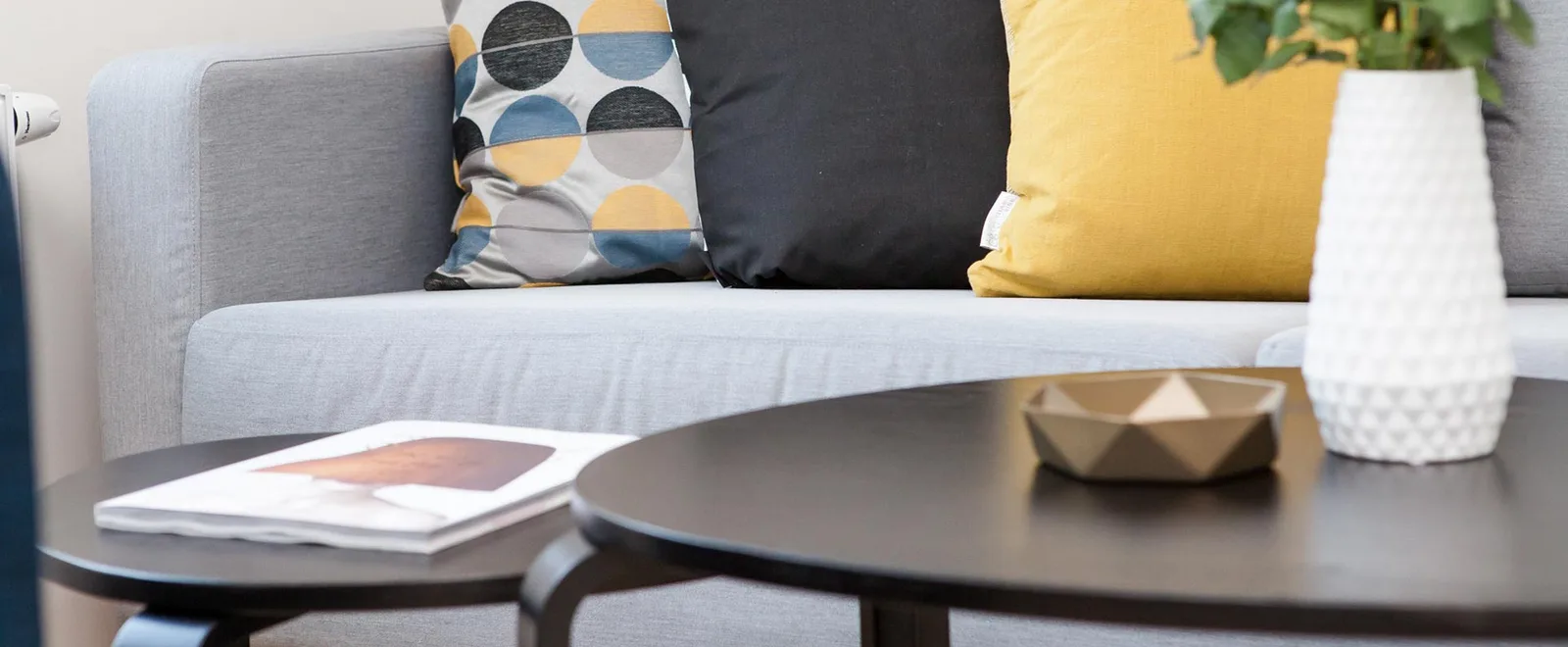 Modernes Wohnzimmer mit grauem Sofa, bunten Kissen und Fotobuch auf Tisch