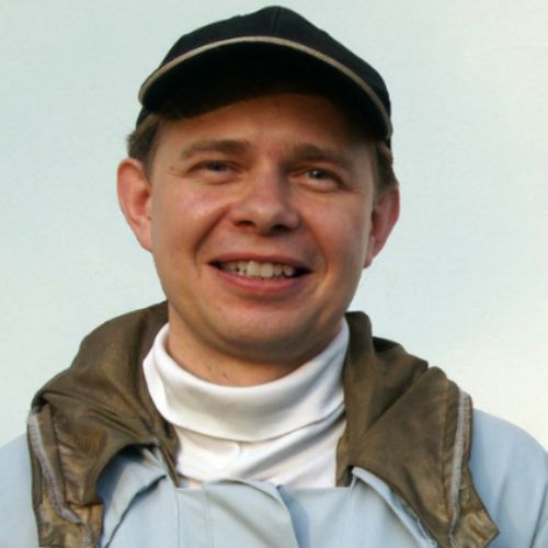 Porträtfoto von Ulrich Weiner, Mann mit Kappe, brauner Weste und weißem Rollkragenpullover