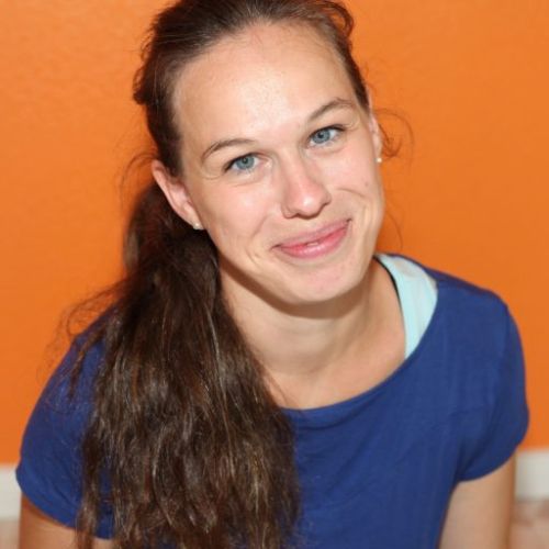 Ulrike Knuth, Frau mit braunen Haaren vor orangem Hintergrund, trägt blaues Shirt