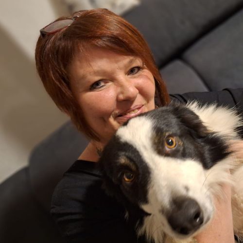 Porträt von Natascha Zauner mit rotbraunen Haaren, hält schwarzweißen Hund