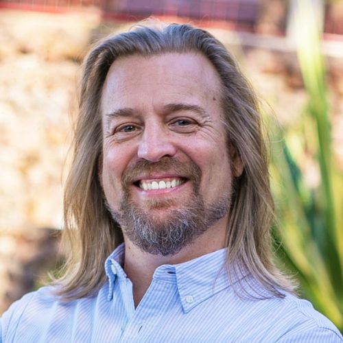 Porträt von Dr. Marc Stollreiter, Mann mit langen blonden Haaren und Bart