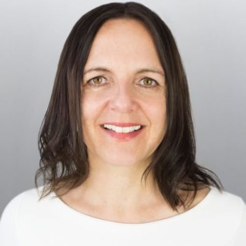 Judith White, Frau mit dunklen Haaren vor grauem Hintergrund, freundliches Lächeln