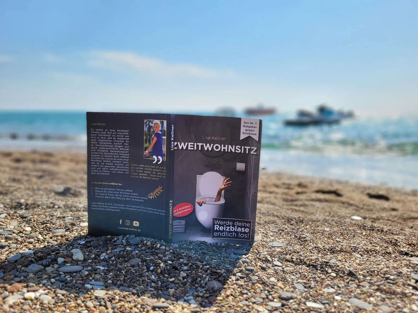 Zweitwohnsitz Buch aufgeschlagen am Strand mit Meer im Hintergrund