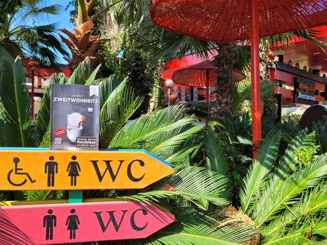 Zweitwohnsitz Buch neben farbigen WC-Hinweisschildern im Restaurant