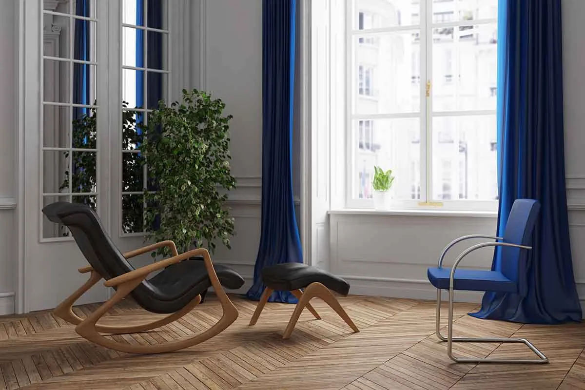Modernes Praxis-Interieur mit schwarzem Sessel, blauem Stuhl und großen Fenstern