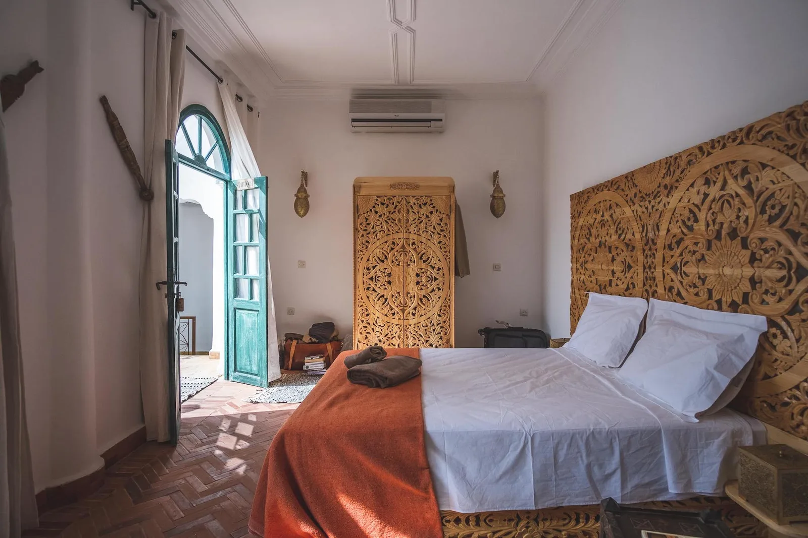 Luxus-Schlafzimmer mit geschnitztem Holzbett, marokkanischen Holzpanelen und Mosaikboden