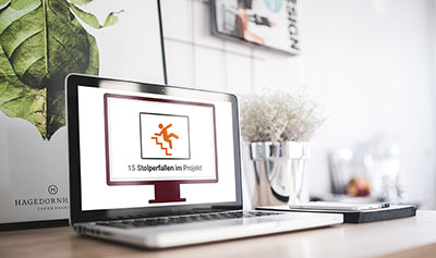 Laptop zeigt Kursstartseite 15 Stolperfallen im Projekt mit Logo und Kursinhalt auf Schreibtisch
