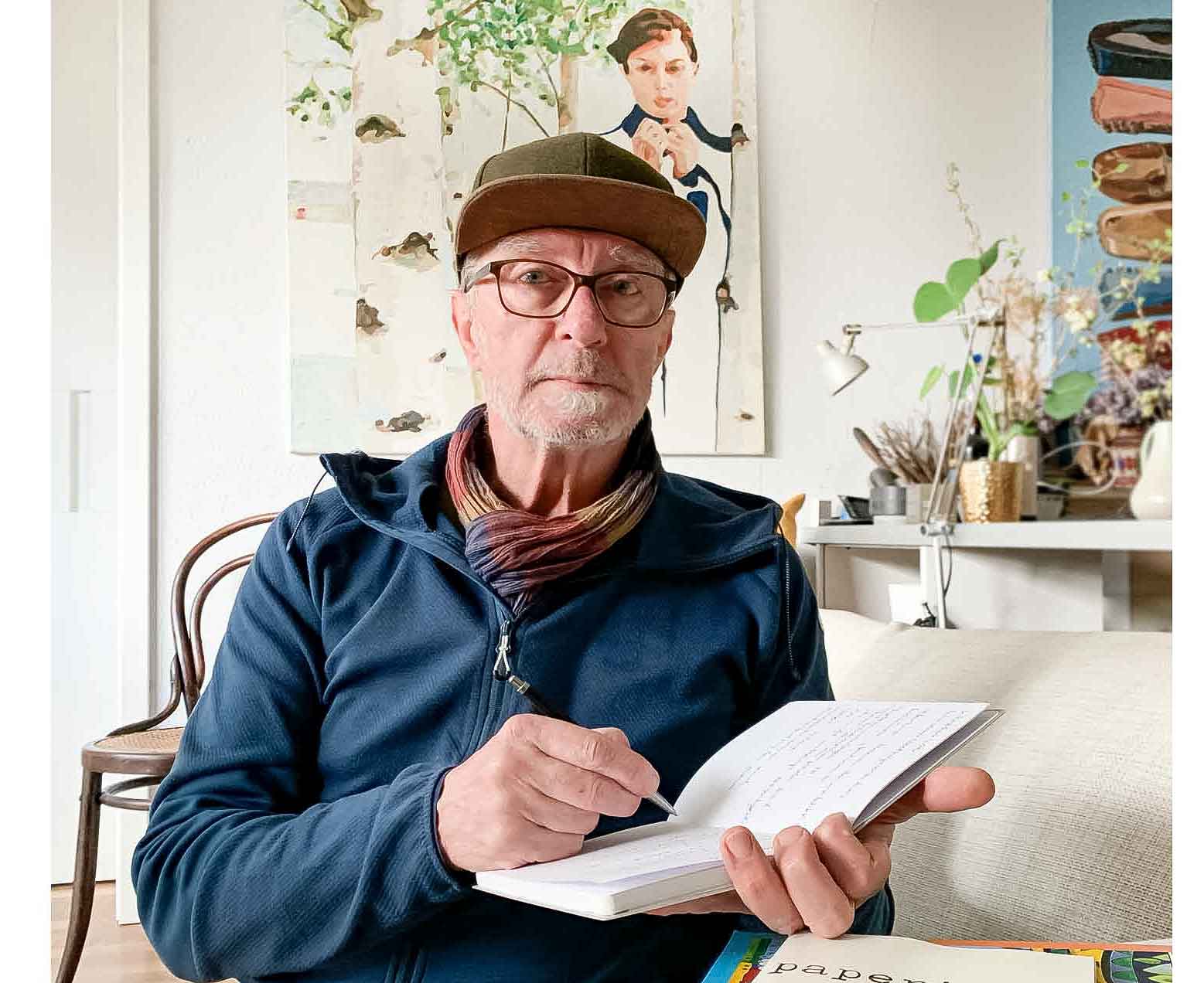 29 Wege Micro-Abenteuer – E-Book mit Mikroabenteuer-Ideen 10 Autor Ralf K. Röttjer sitzt am Schreibtisch mit Notizbuch, Kreativstudio im Hintergrund
