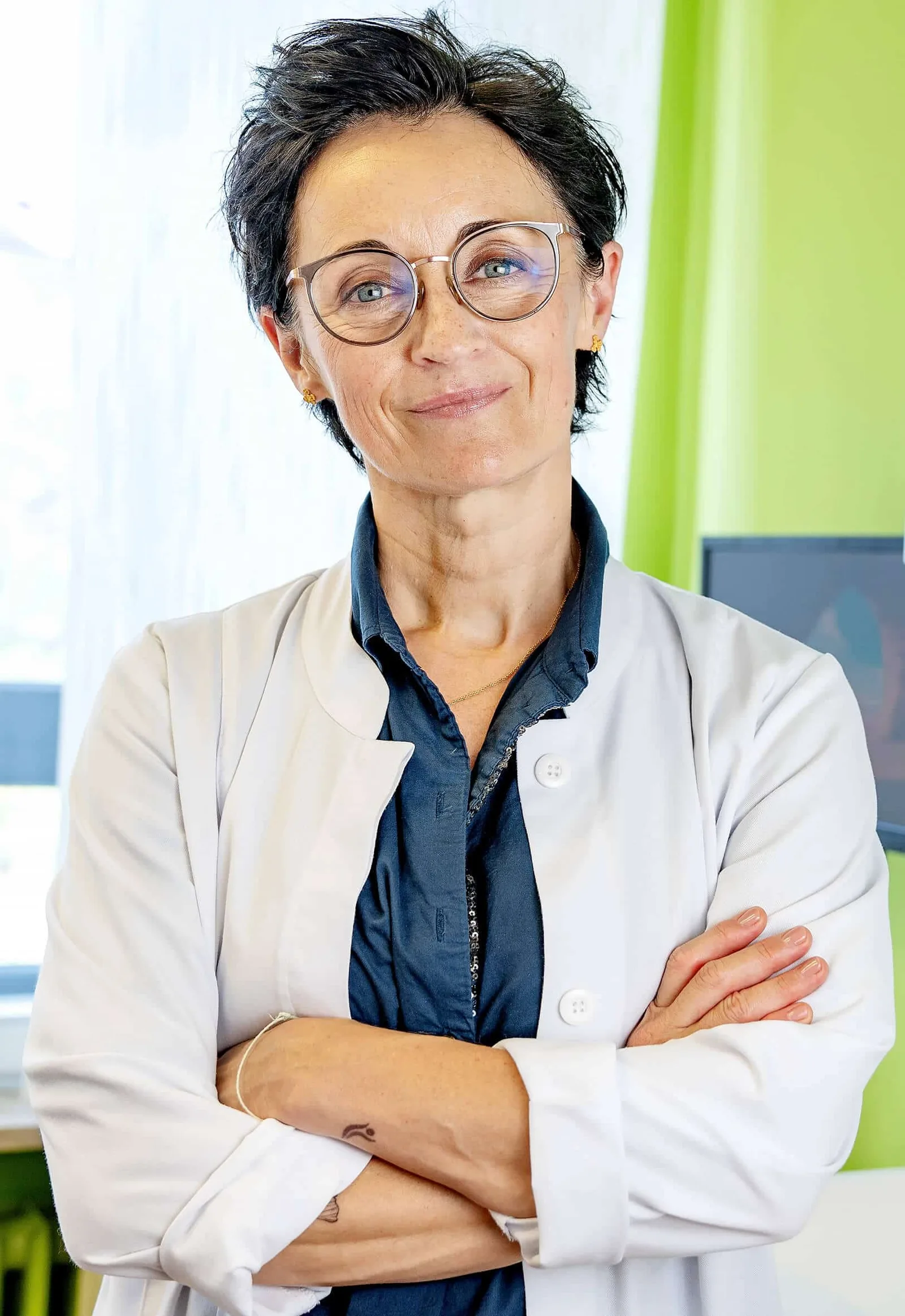 Porträt von Dr. Annette Jasper, Zahnärztin mit Brille in weißem Arztkittel