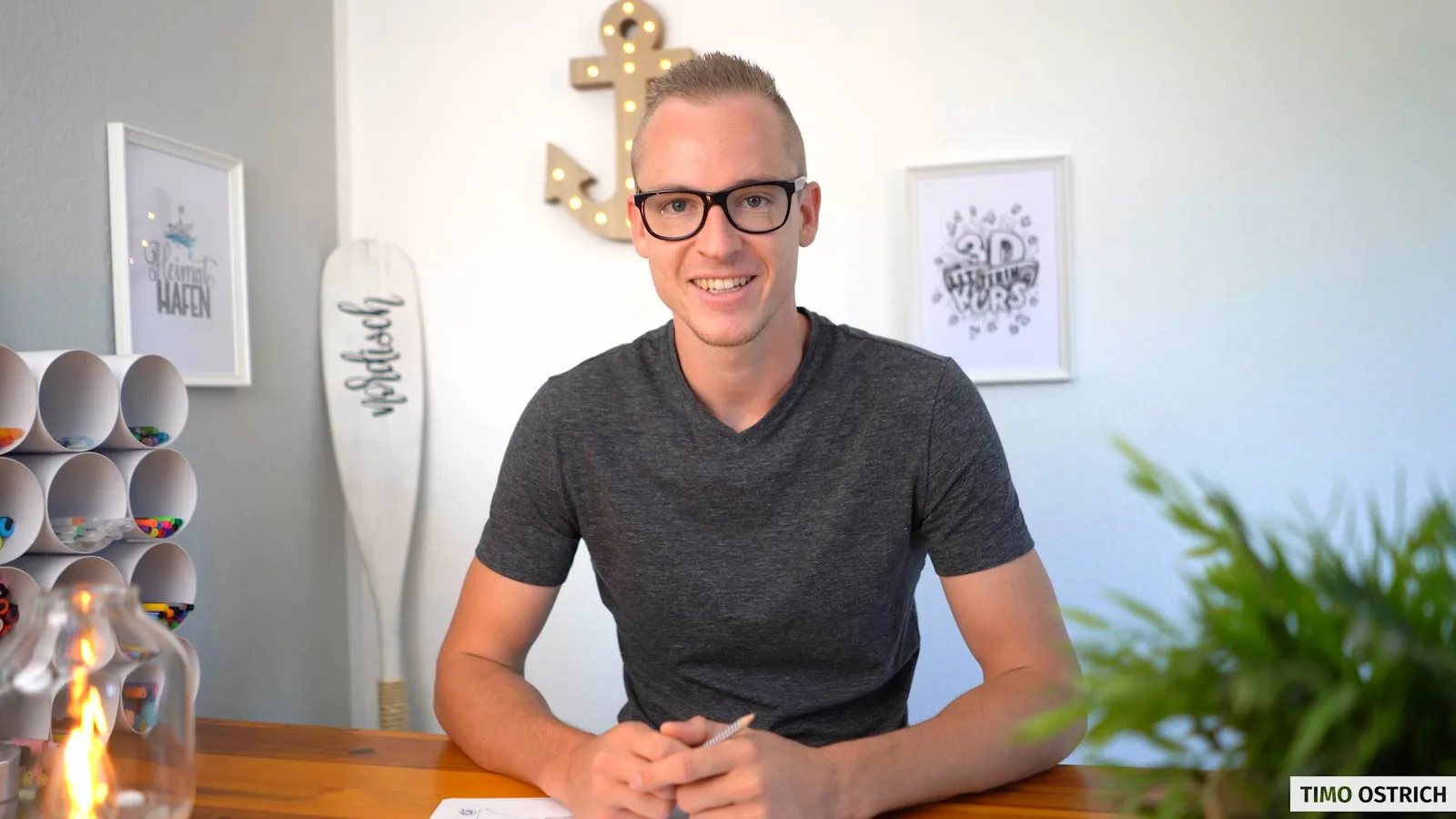 Timo Ostrich sitzt an Schreibtisch mit 3D-Lettering-Arbeiten im Hintergrund