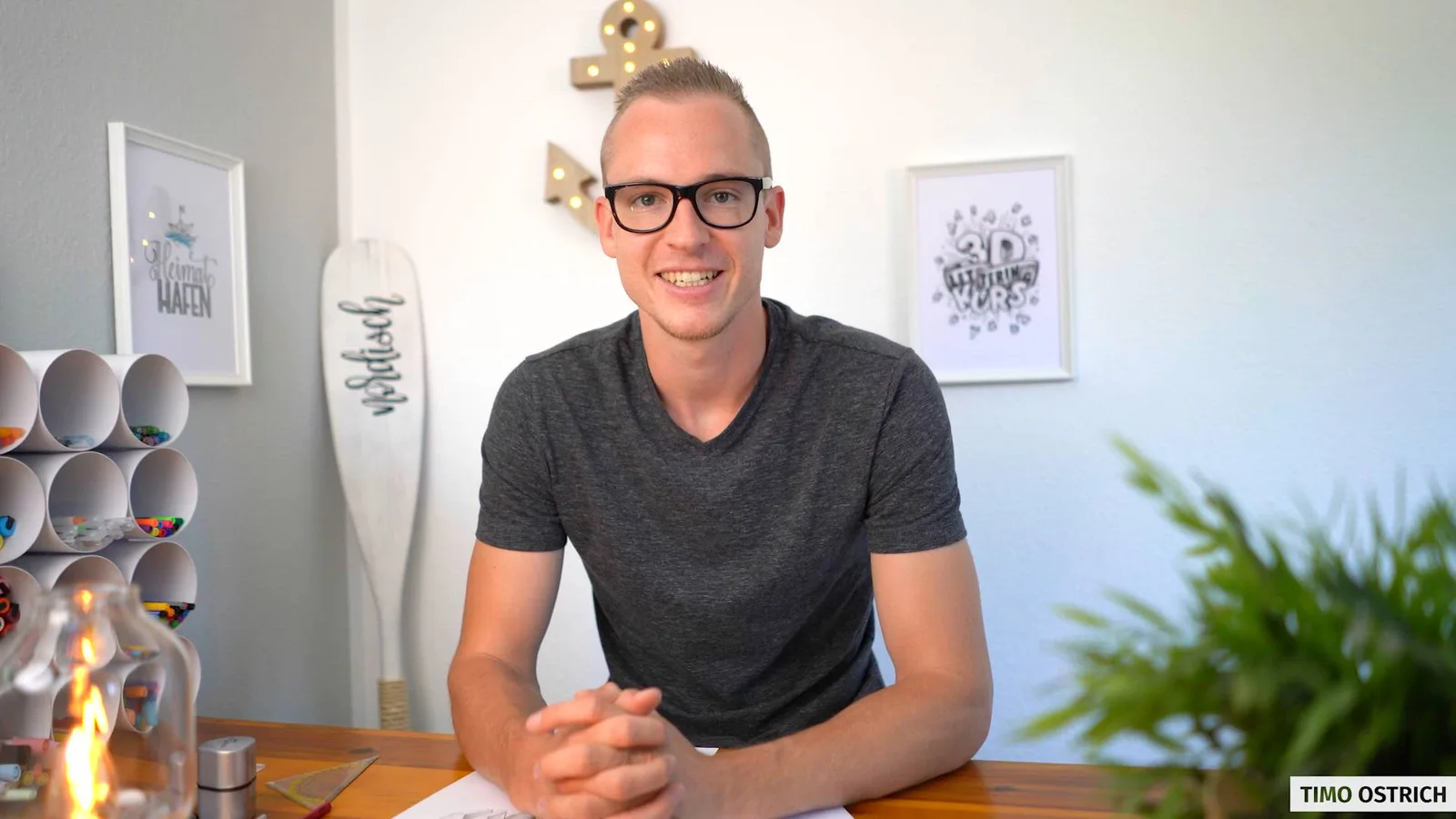 Timo Ostrich sitzt an einem Schreibtisch in seinem Büro und lächelt in die Kamera