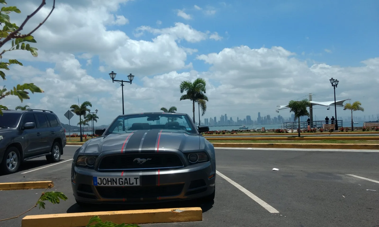 Ford Mustang Cabrio mit Kennzeichen JOHNGALT an Flughafen in Panama mit Skyline im Hintergrund