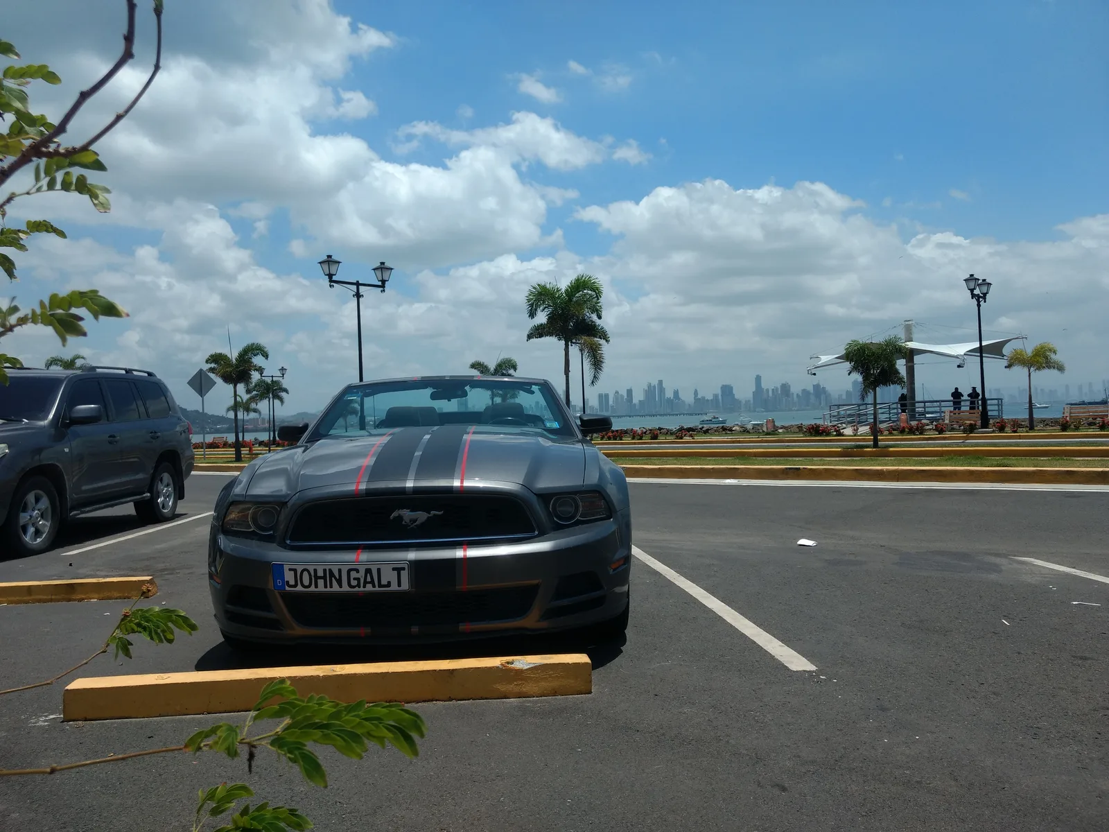 Ford Mustang Cabrio mit Kennzeichen JOHNGALT an Flughafen in Panama mit Skyline im Hintergrund