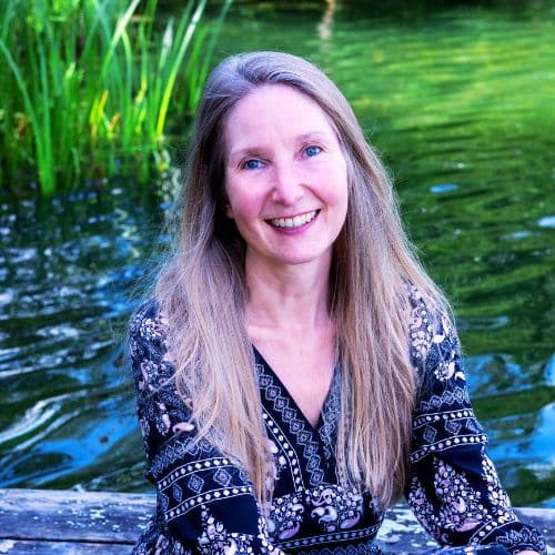 Inga Dalhoff, Frau mit lange Haaren vor See und grüner Vegetation lächelnd
