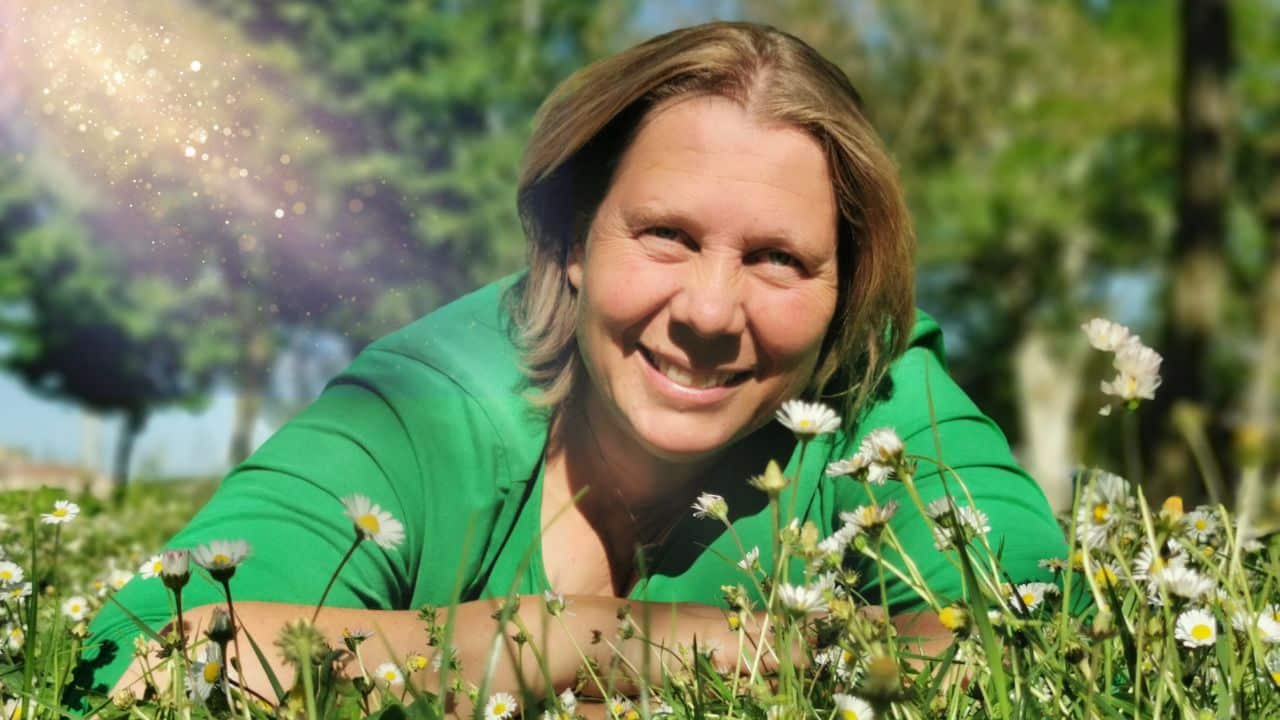 Heike Engel lächelt in grünem Shirt auf Blumenwiese, Lichteffekte