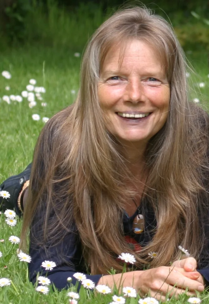 Rita Lüder auf Gänseblümchenwiese, Frau mit braunem Haar lächelnd