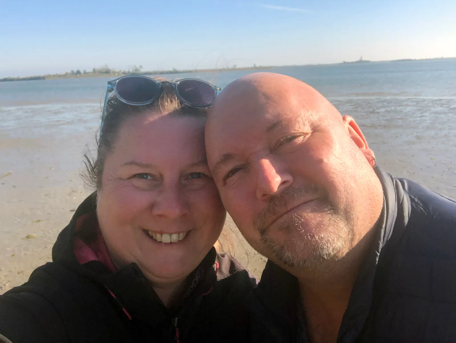Jasmin und Gerhard, Paar lächelt am Strand vor Wasser
