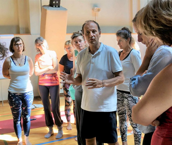 Remo Rittiner unterrichtet Yogagruppe in Sporthalle mit Matten und Teilnehmern