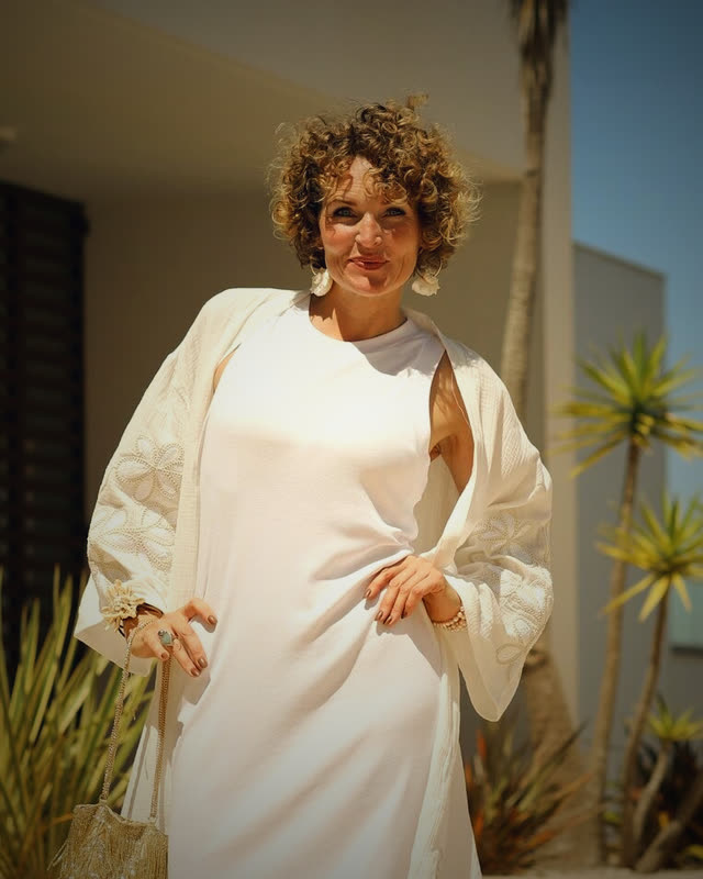 Frau in weißer Bluse vor moderner Architektur mit Pflanzen und natürlichem Licht