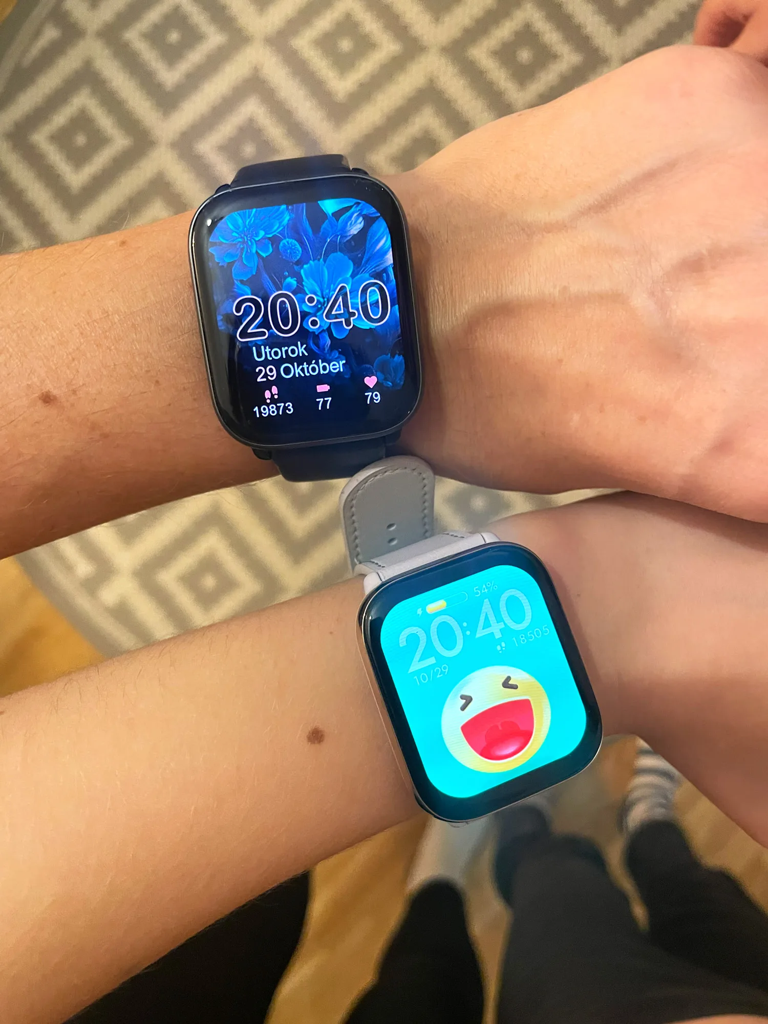 Zwei Smartwatches am Handgelenk zeigen Fitness-Tracking mit Schrittzähler und Emoji